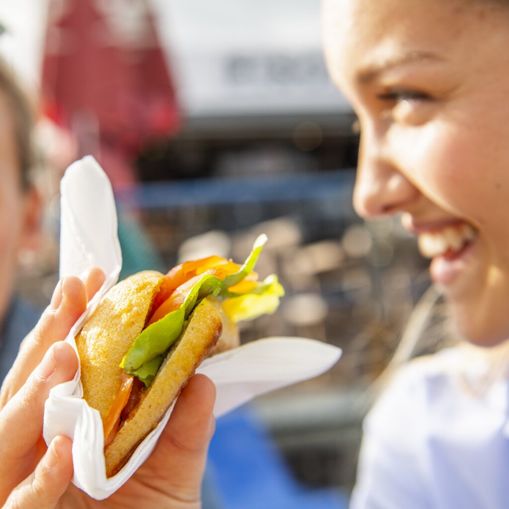 A woman holds a vegan fish sandwich in her hand