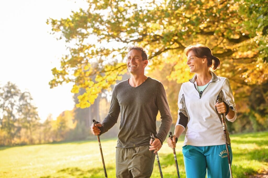 Zwei Menschen beim Nordic Walking in einem herbstlichen Wald in Bad Wörishofen