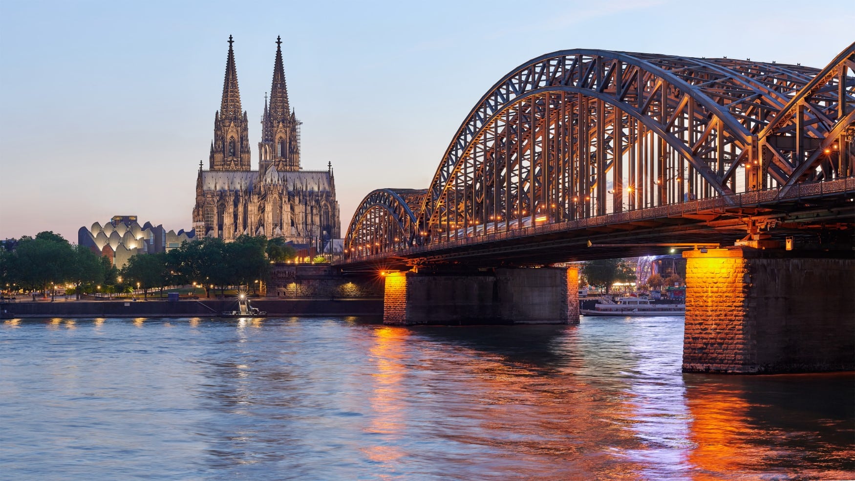 Die Hohenzollernbrücke in Köln im Abendlicht, im Hintergrund der Dom