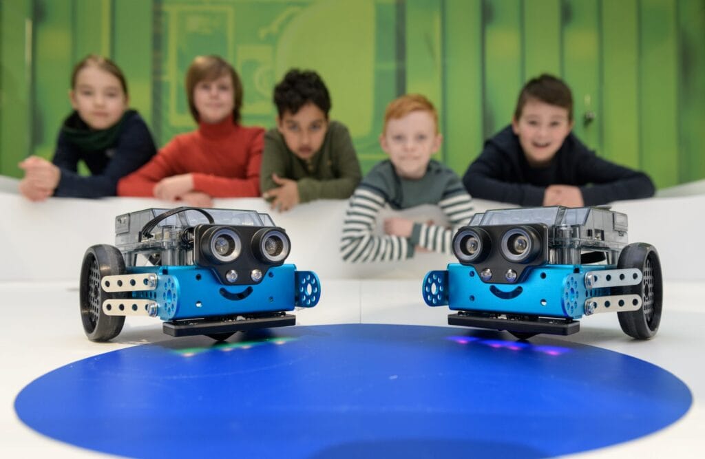 Zwei kleine Roboter auf Rollen im Technoseum in Mannheim, im Hintergrund sieht man einige Kinder