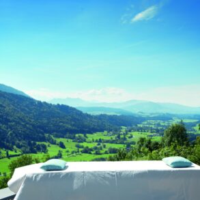 Vor einem malerischen Alpenpanorama steht eine Wellnessliege im Freien