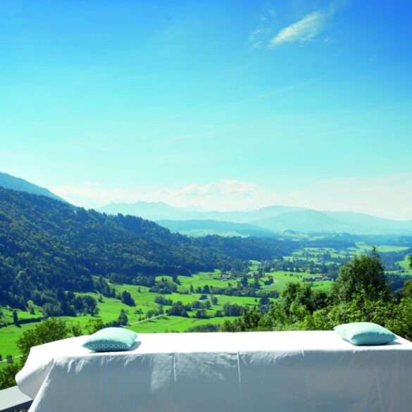 Vor einem malerischen Alpenpanorama steht eine Wellnessliege im Freien