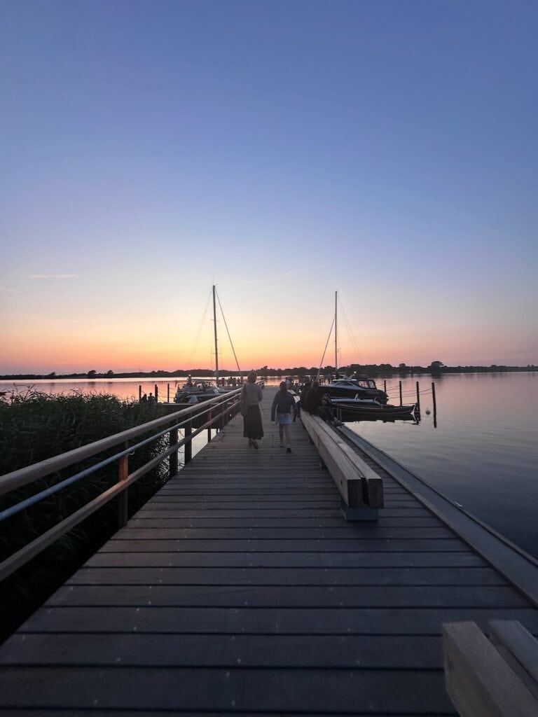 Zwei Personen laufen im Sonnenuntergang über einen Steg auf der Schlei