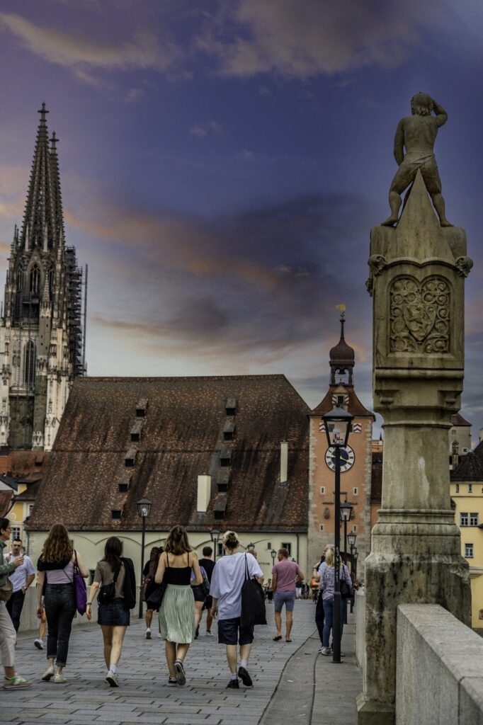 Menschen gehen über die Steinerne Brücke in Regensburg