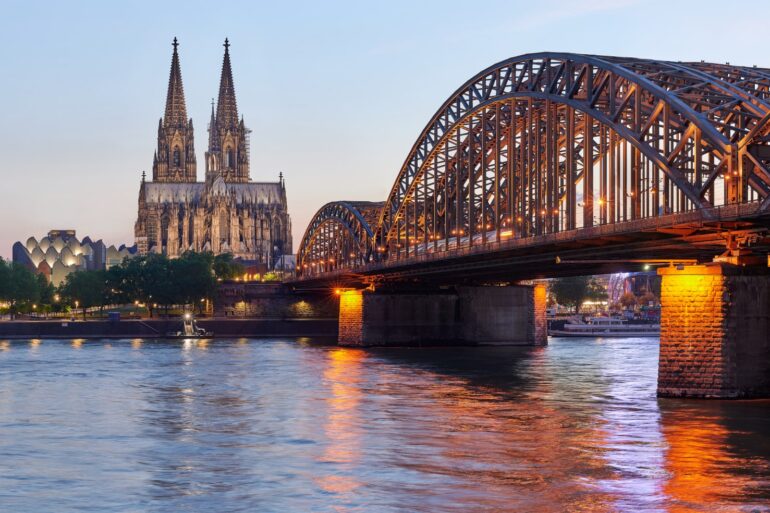 The Hohenzollernbrücke in Cologne leading across the Rhine towards the Cologne Cathedral at night