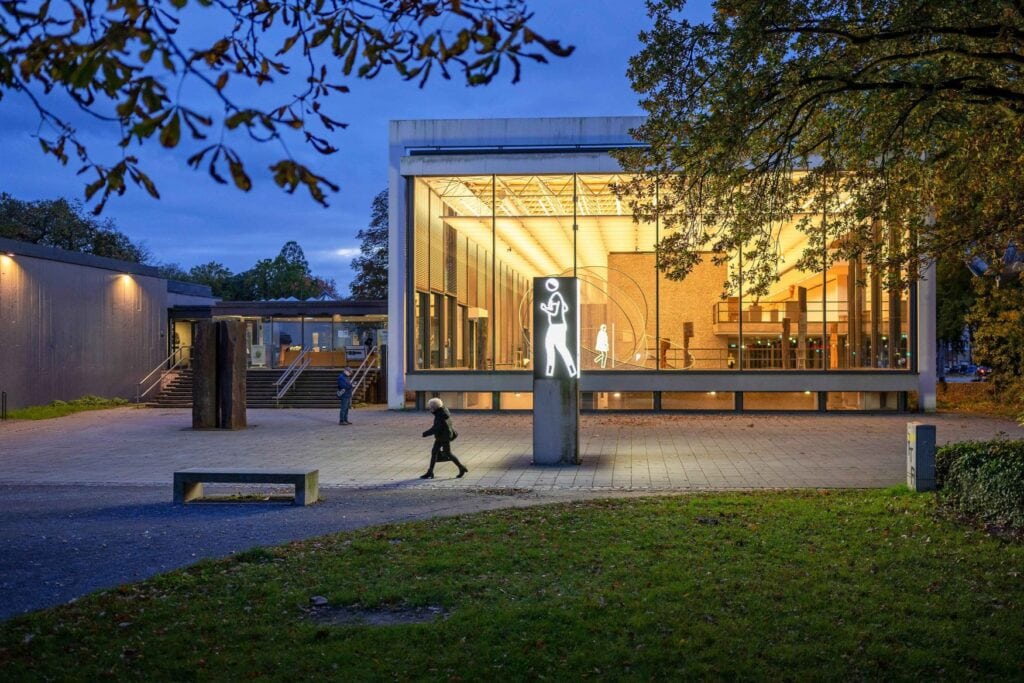 Eine leuchtende Skulptur vor dem Duisburger Lehmbruckmuseum in der Abenddämmerung