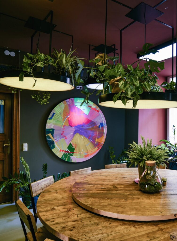 Restaurant Bonvivant in Berlin (cocktail bistro/lifestyle). Interior view with round table seating several people. Room decorated with various green plants.