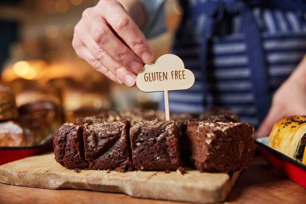 A man puts a “gluten free” sign on a batch of brownies.