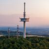 Drohnenaufnahme des Funkturms auf dem Vogelsberg in Hessen, im Hintergrund scheint sanft das Licht der Abenddämmerung