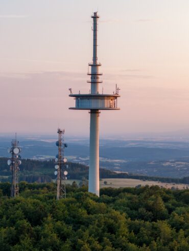Drohnenaufnahme des Funkturms auf dem Vogelsberg in Hessen, im Hintergrund scheint sanft das Licht der Abenddämmerung