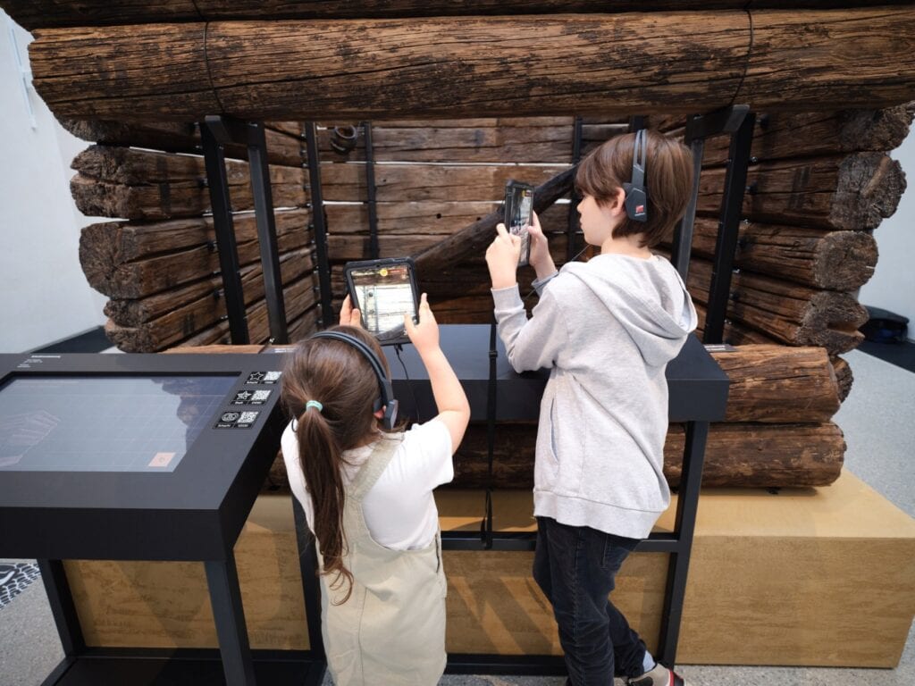 Zwei Kinder nutzen das digitale Zusatzangebot vor einem Exponat im Archäologischen Museum München