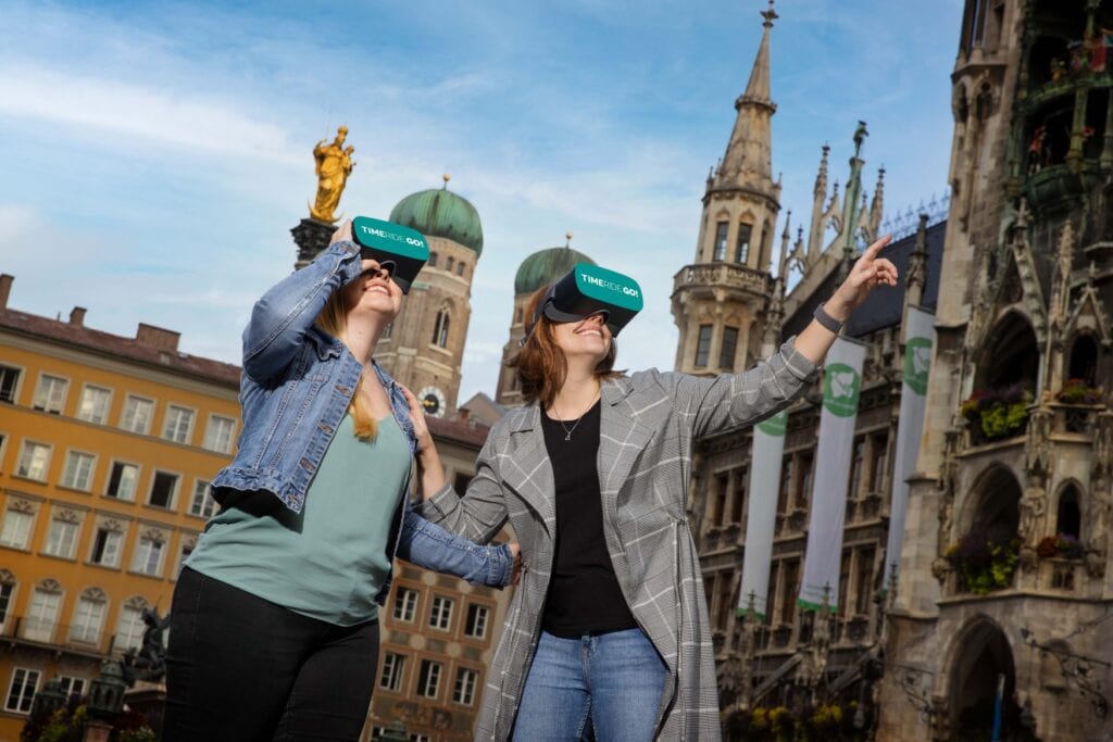 Zwei Menschen mit VR-Brille laufen durch München