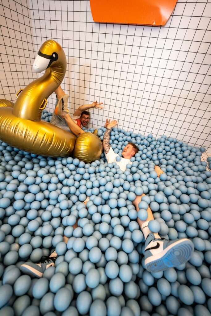 A young man "splashing" around in a ball pit