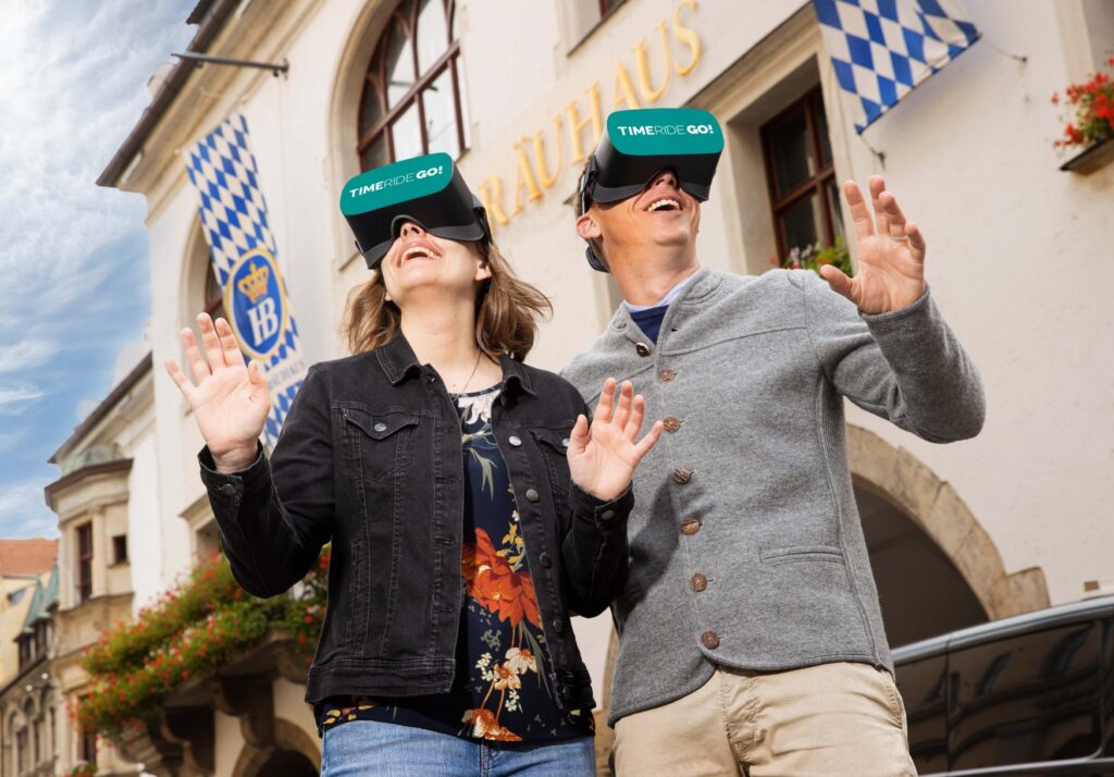 Two people wearing VR goggles walk through Munich.