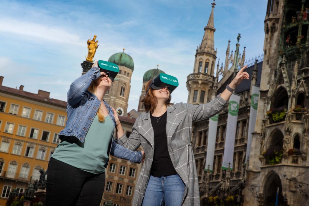 Two people wearing VR glasses walk through Munich.