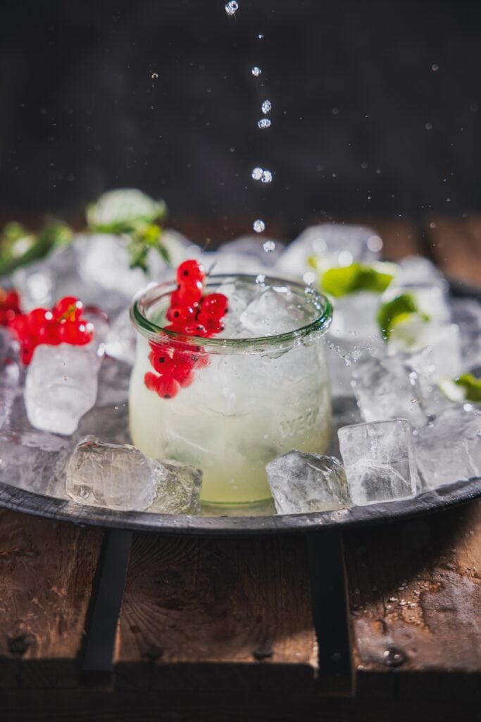 Ein in einer Schale mit Eiswürfeln angerichtetes Glas Clear Milk Cocktail