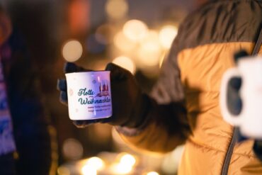 Eine Person hält eine Tasse Glühwein in der Hand