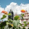 Eine Statue vor einem Haus mit Fachwerkelementen, davor Blumen