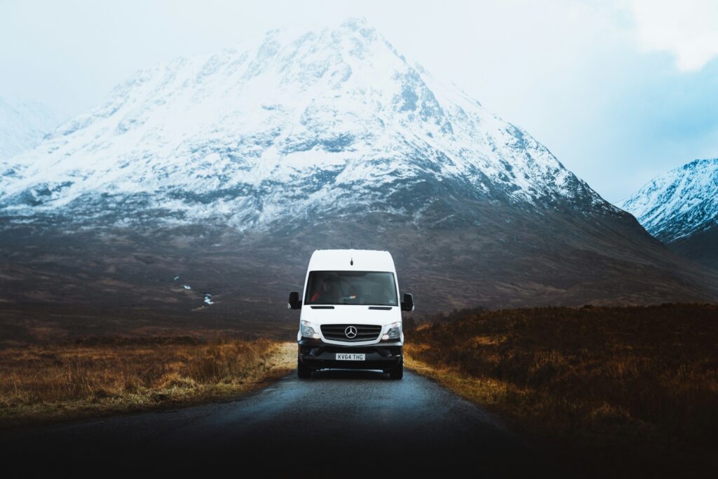 A camper van is driving from a snowy mountain directly towards the viewer