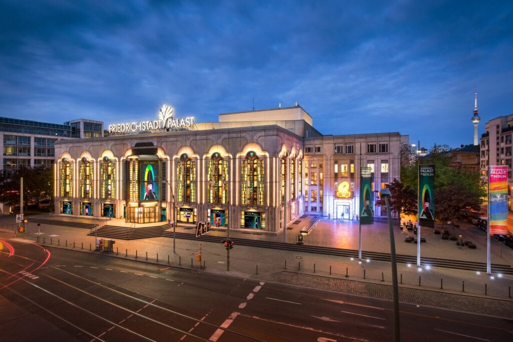 Der Friedrichsbau in Berlin von außen, in der Dämmerung und hell erleuchtet