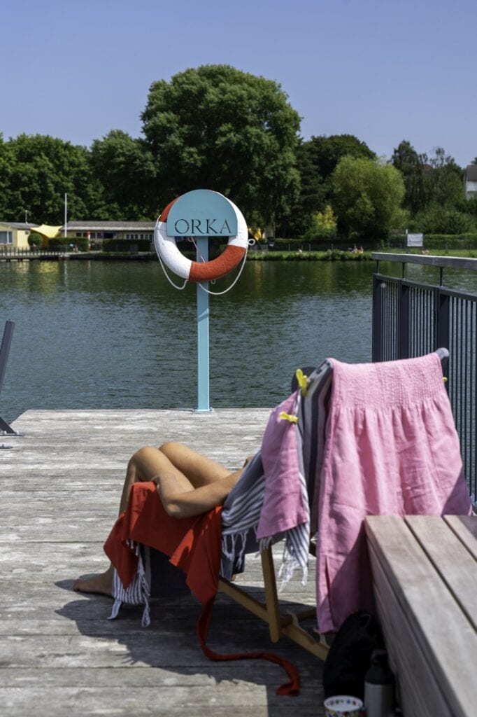 Eine Person sonnt sich auf einer Liege im Naturbad Falkenwiese in Lübeck