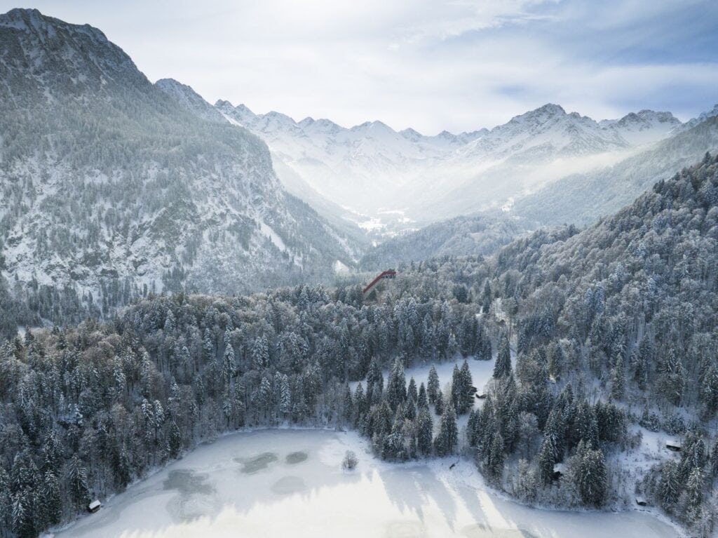 Ein verschneites Tal in den Alpen bei Oberstdorf, die Sonne hoch am Himmel