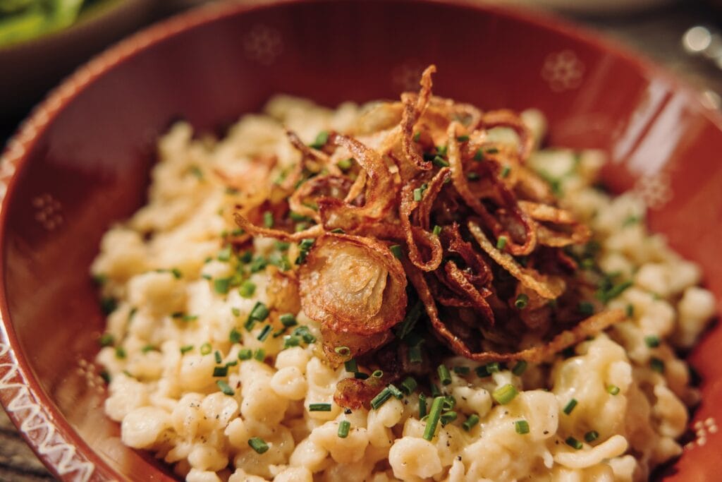 Eine Portion Kässpätzle mit Zwiebeln in Nahaufnahme