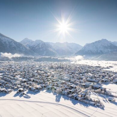 Die Sonne scheint auf das verschneite Oberstdorf im Winter in den Alpen