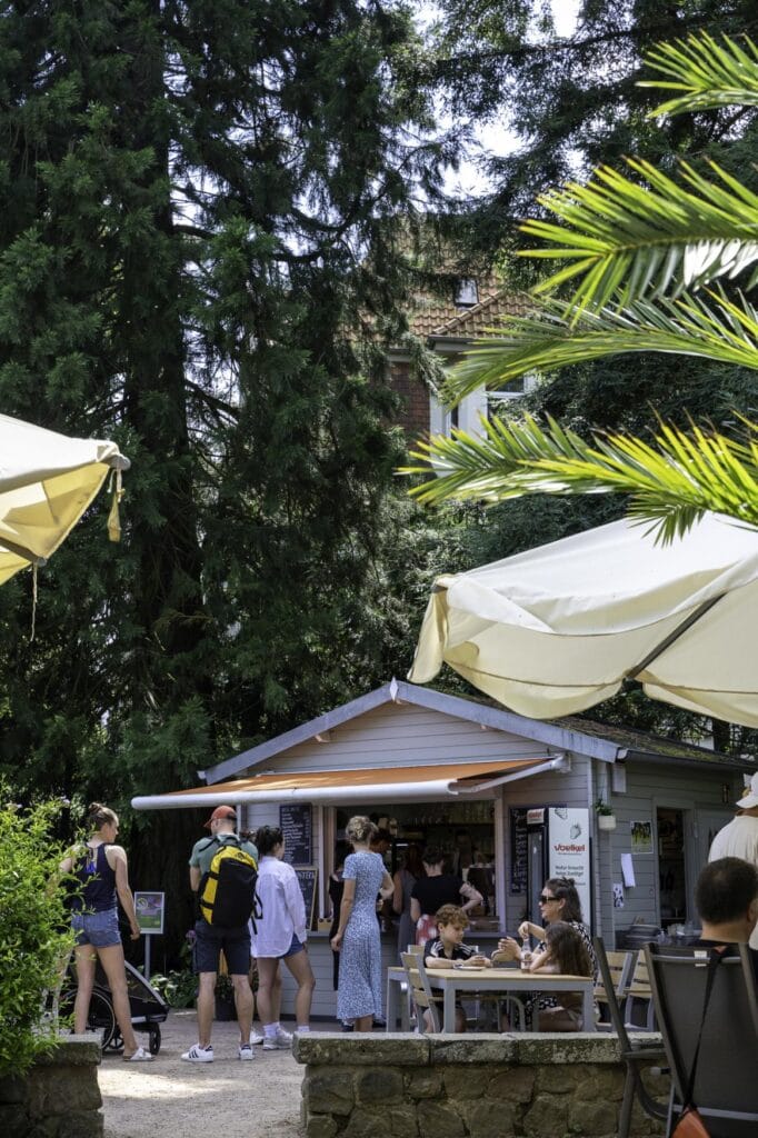 Ein Kiosk im Schulgarten Lübeck, mit zahlreichen Besuchern am Fenster und den Sitzplätzen davor