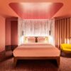 A room at Tribe Düsseldorf, with pink lighting and yellow upholstered furniture