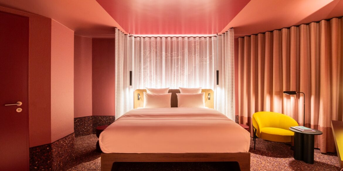 A room at Tribe Düsseldorf, with pink lighting and yellow upholstered furniture