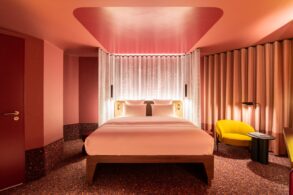 A room at Tribe Düsseldorf, with pink lighting and yellow upholstered furniture