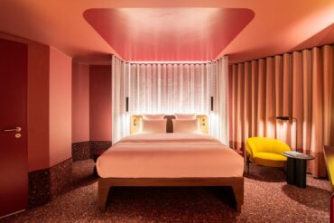 A room at Tribe Düsseldorf, with pink lighting and yellow upholstered furniture