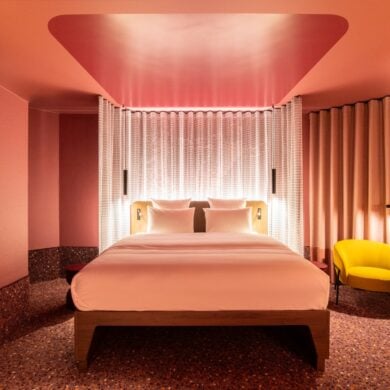 A room at Tribe Düsseldorf, with pink lighting and yellow upholstered furniture