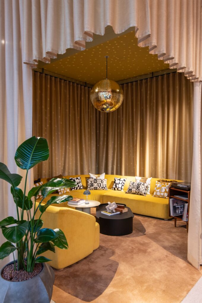 A corner lounge at Tribe Düsseldorf, with yellow upholstery and a disco ball hanging from the ceiling