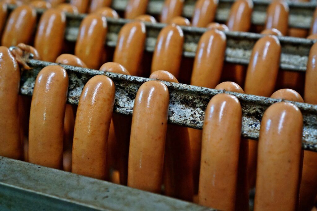 Several pairs of bockwursts hanging on a rod to cook in their broth