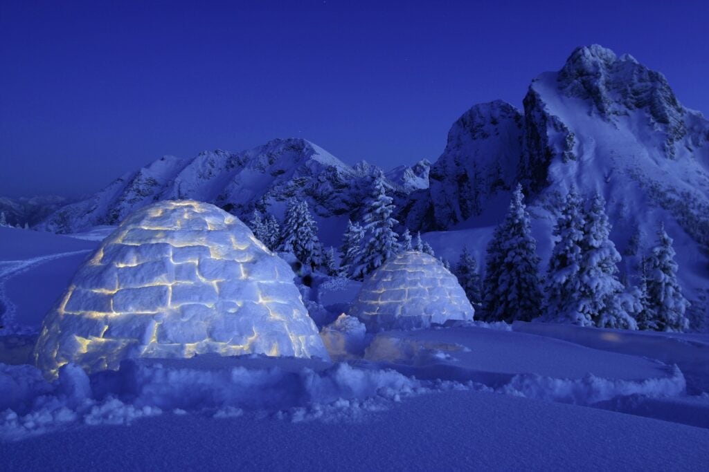 Ein Iglu im verschneiten Pfronten im Allgäu bei Nacht. Von innen wird es beleuchtet.