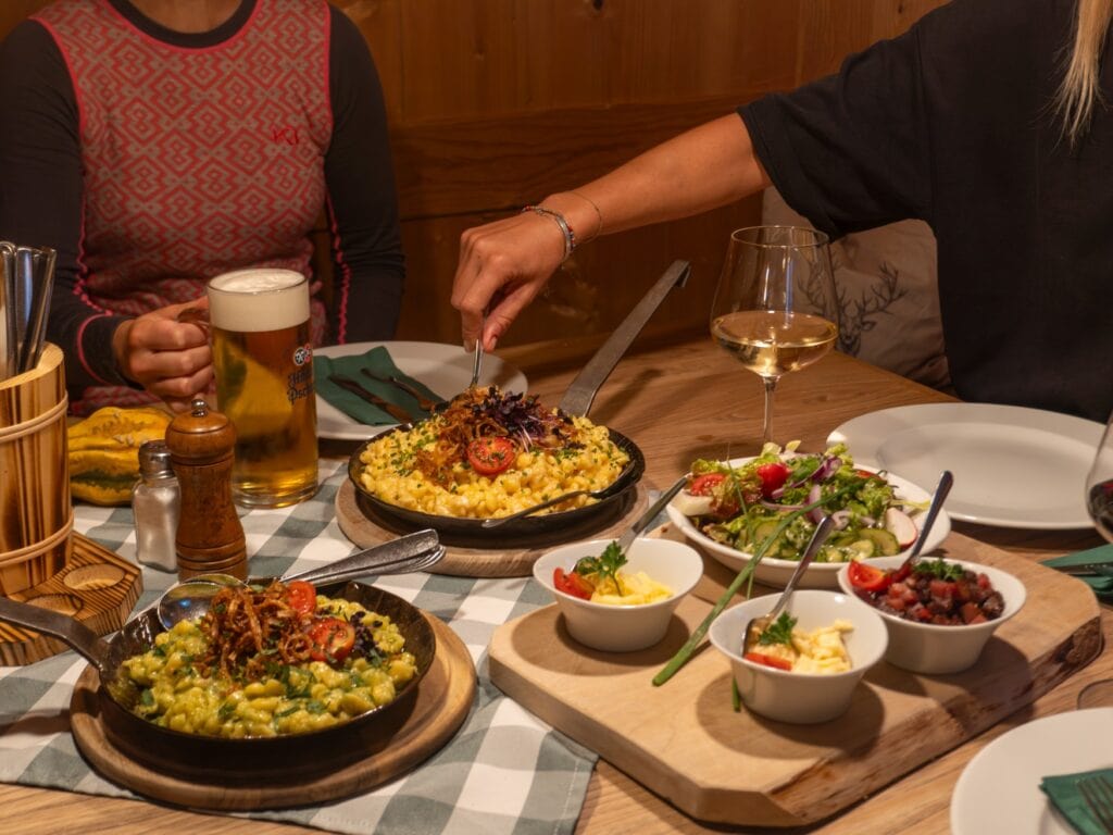 Eine deftige Vesper auf einem Holztisch, mit Kässpatzn als Hauptmahlzeit