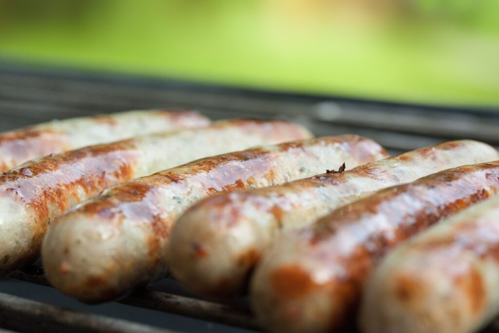 Several Nuremberg grilled sausages are lying next to each other on a grill.