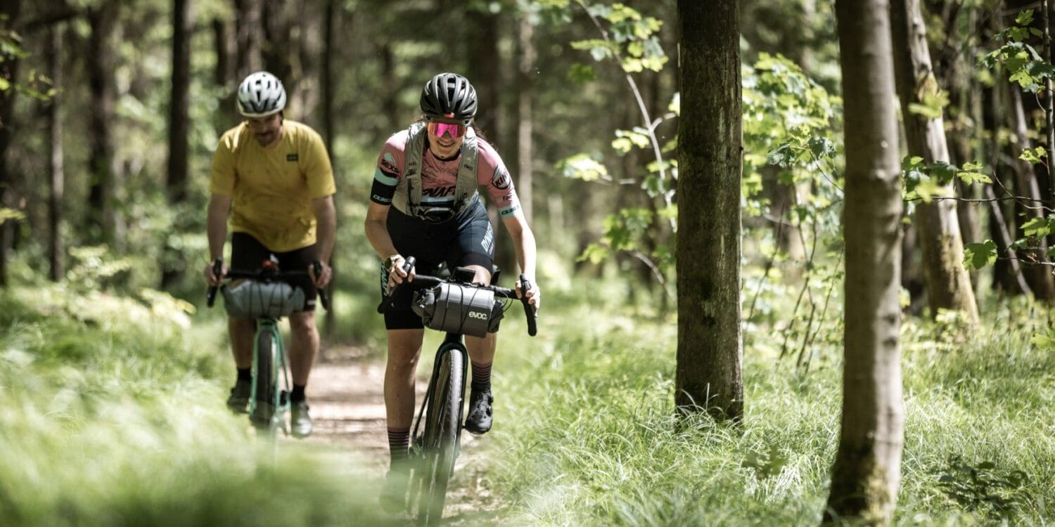 Two cyclists ride through a forest in the Wesenitztal in Saxony.