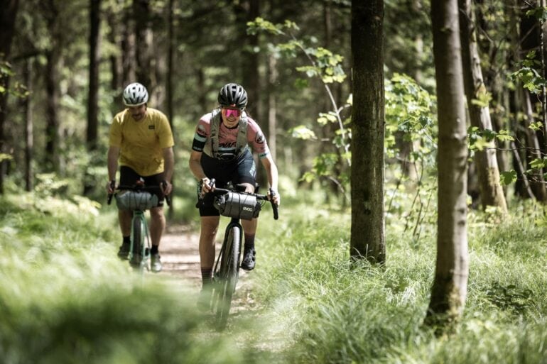 Two cyclists ride through a forest in the Wesenitztal in Saxony.