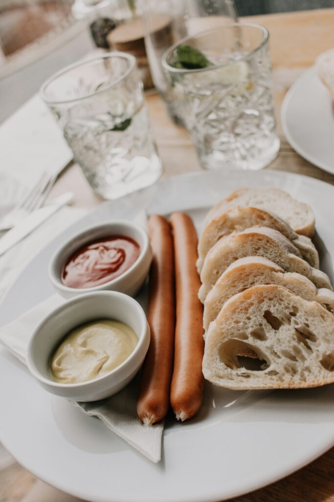 Ein Paar Wiener Würstchen mit Brot und Soßen auf einem Teller