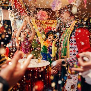 Menschen in Kostümen feiern in einer Kneipe Karneval, der Großteil des Bildes ist von Konfetti ausgefüllt.