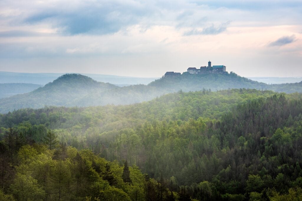 Aussicht auf den Thüringer Wald, über dem in der Ferne die Wartburg thront - ein Hotspot zum Waldbaden in Deutschland