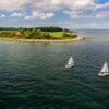 Zwei Segelboote fahren auf der Ostsee, im Hintergrund die Insel Fehrmarn. Ein beliebtes Ausflugsziel von Kiel aus