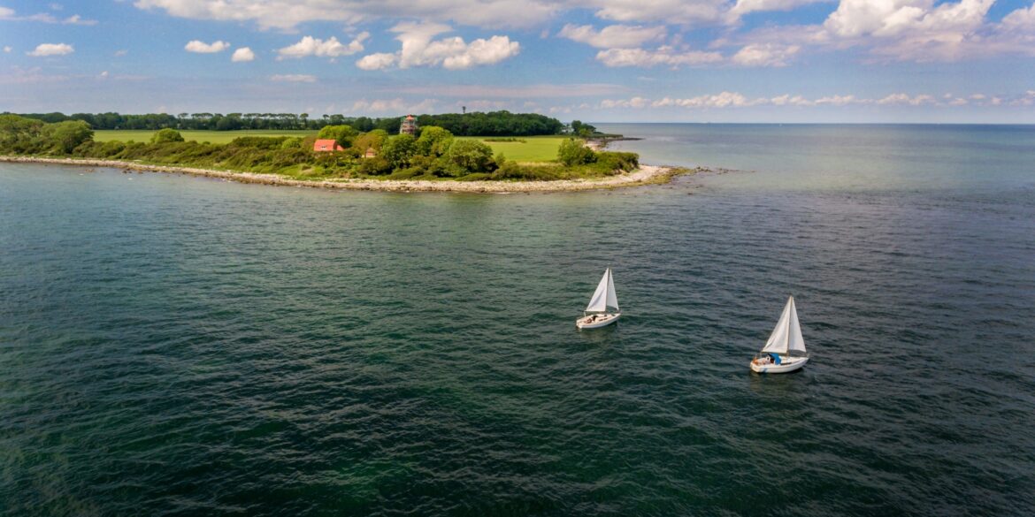 Zwei Segelboote fahren auf der Ostsee, im Hintergrund die Insel Fehrmarn. Ein beliebtes Ausflugsziel von Kiel aus