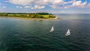 Zwei Segelboote fahren auf der Ostsee, im Hintergrund die Insel Fehrmarn. Ein beliebtes Ausflugsziel von Kiel aus
