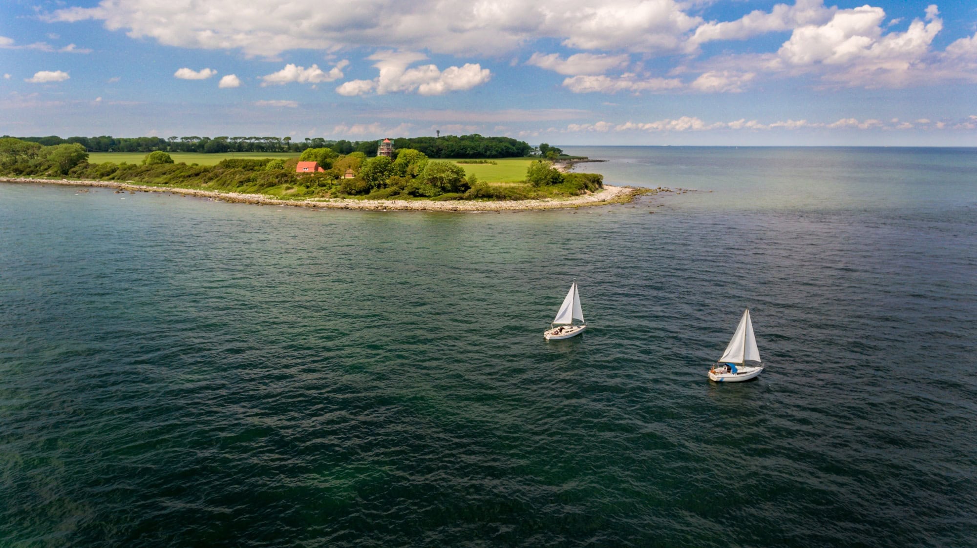 Zwei Segelboote fahren auf der Ostsee, im Hintergrund die Insel Fehrmarn. Ein beliebtes Ausflugsziel von Kiel aus