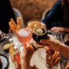 Three people toast with different drinks over a set table