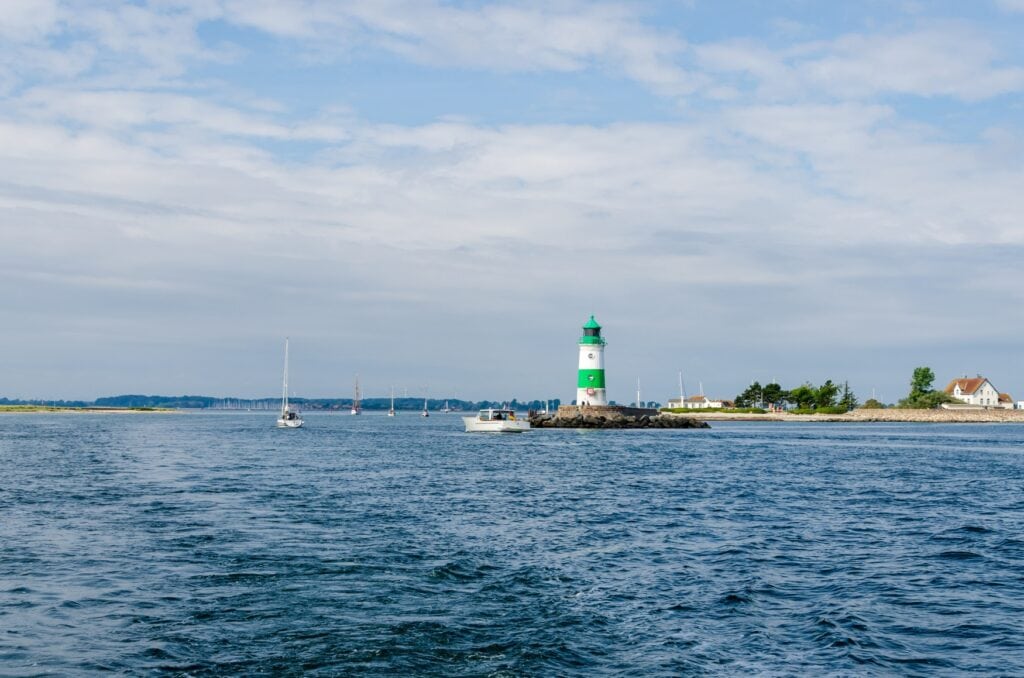 Auf einem langen Vorsprung steht der grün-weiße Leuchtturm von Schleimünde